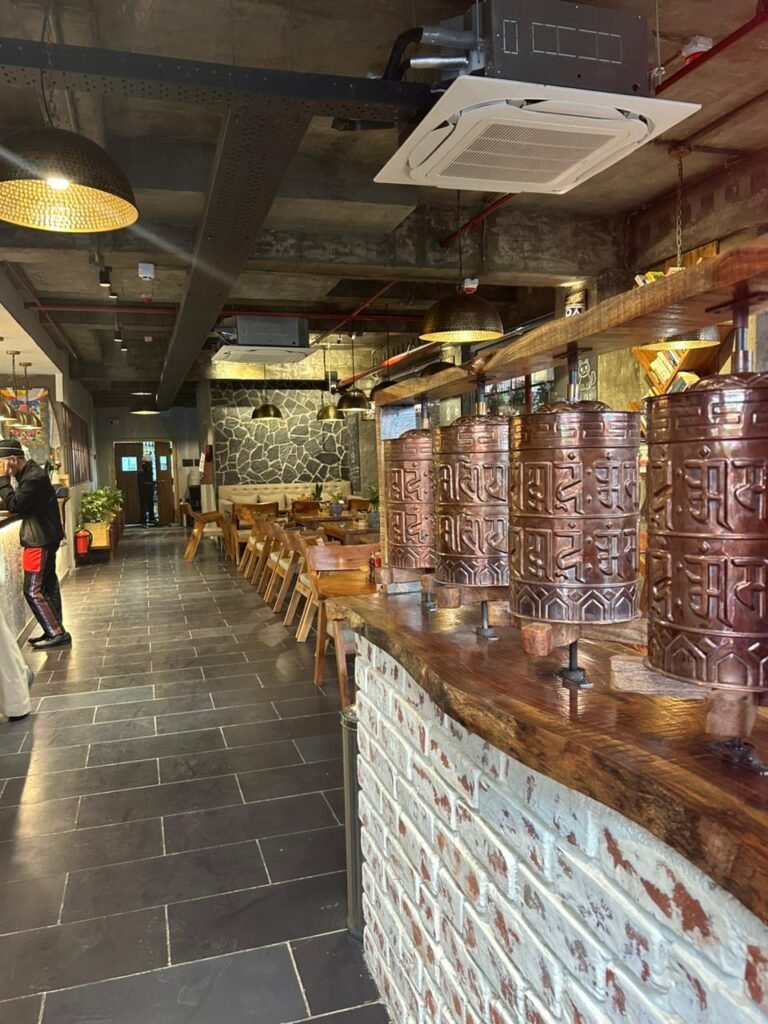 Kalsang main dining area with carved copper prayer wheel columns and wooden tables
