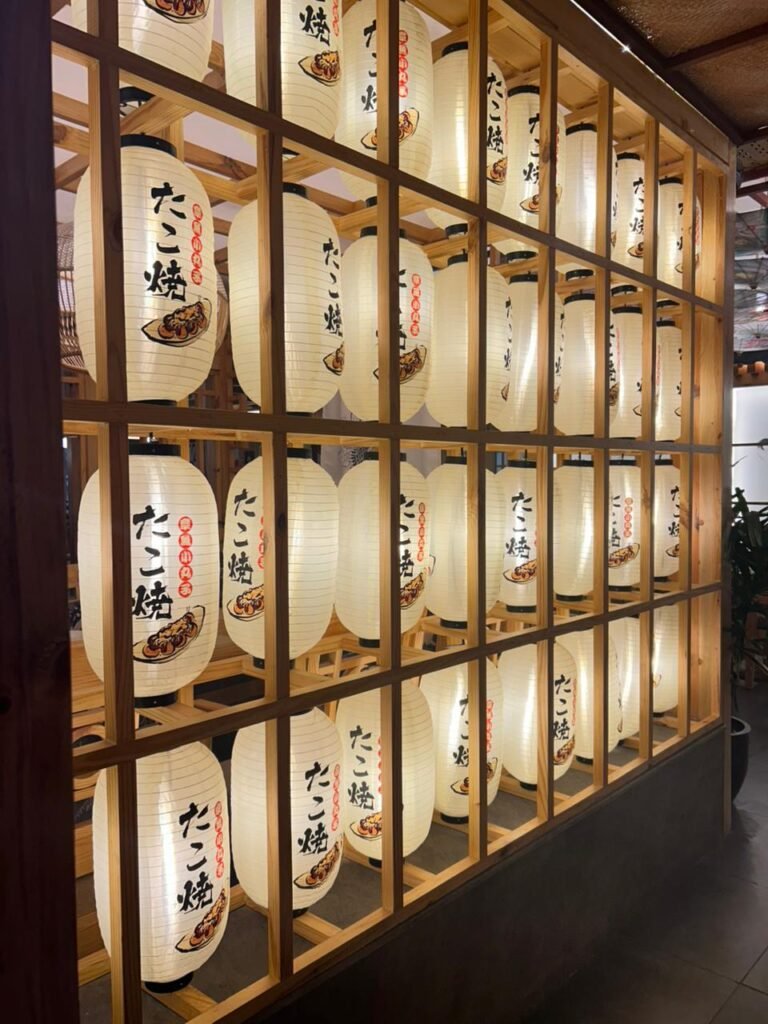 Illuminated Japanese lantern wall with wooden grid at Kalsang Restaurant interior