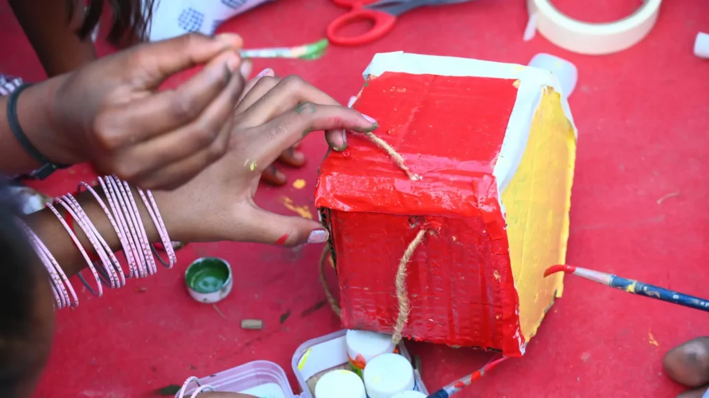 A student paints a bird shelter made from reused cardboard during a Noida environmental activity