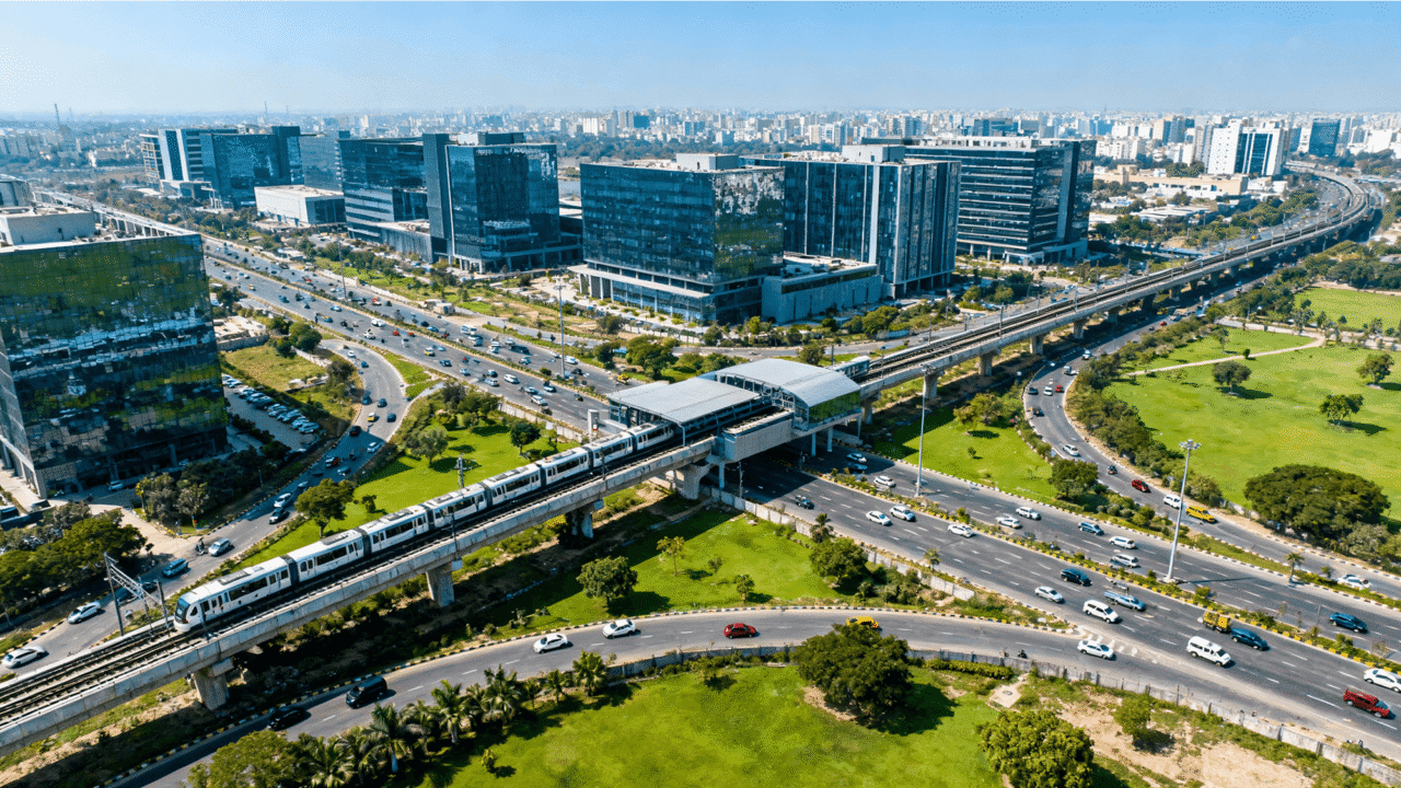 Aerial view of Noida city with modern tech campuses, glass office buildings, metro station, and green urban development