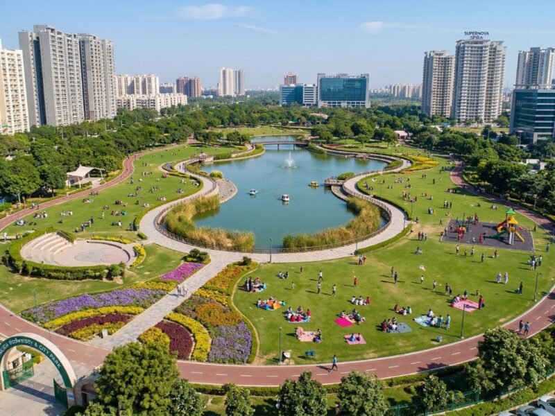 A large urban park with a lake, walking tracks, lawns, and families in Noida