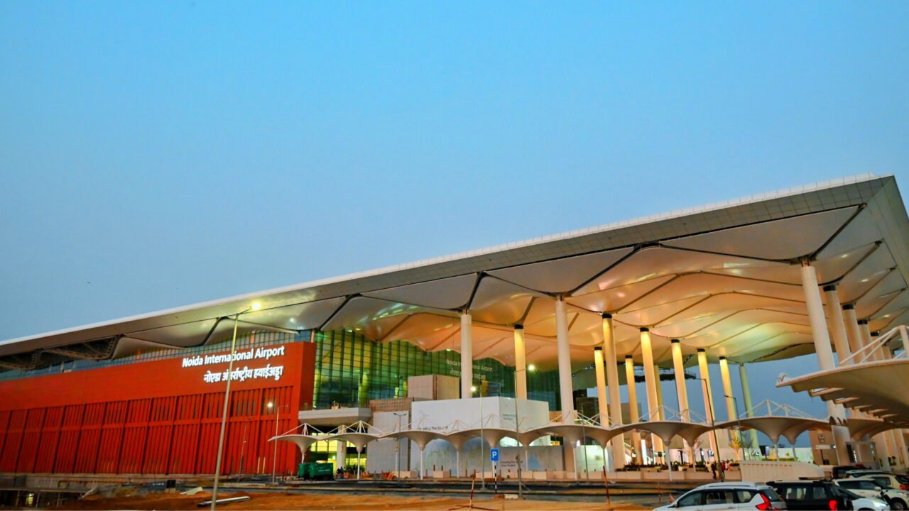 Evening exterior view of Noida International Airport terminal with illuminated facade in Jewar