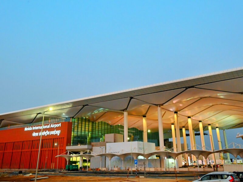 Evening exterior view of Noida International Airport terminal with illuminated facade in Jewar