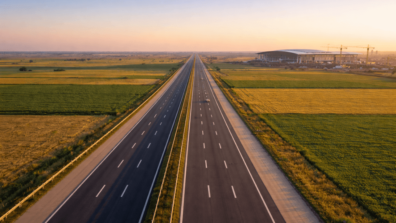 Aerial view of Yamuna Expressway near Greater Noida with Noida International Airport terminal and construction cranes visible in the background, 2026