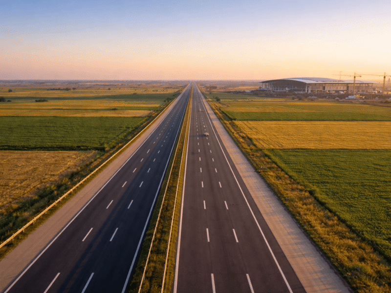 Aerial view of Yamuna Expressway near Greater Noida with Noida International Airport terminal and construction cranes visible in the background, 2026