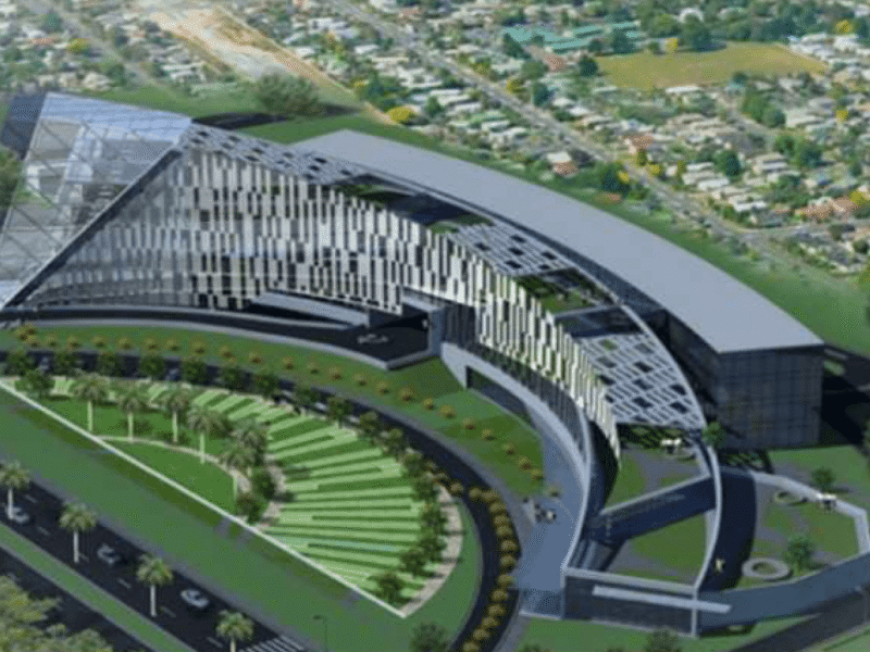 An aerial architectural rendering of the new Noida Authority headquarters in Sector 96, showcasing its modern curved glass facade and green landscaping.