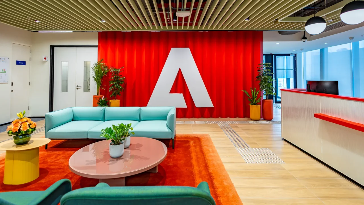 Adobe office reception area in Sector 129 Noida with Adobe logo and modern workplace seating.