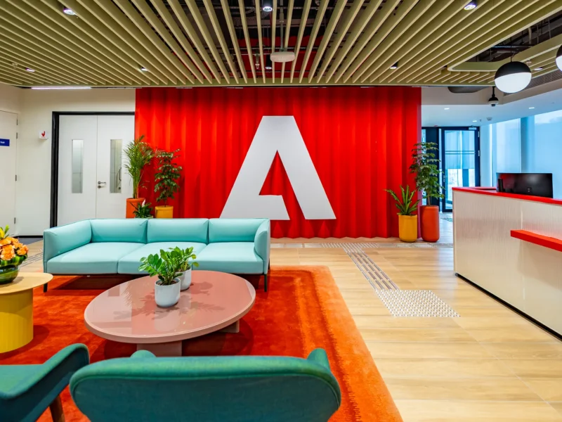 Adobe office reception area in Sector 129 Noida with Adobe logo and modern workplace seating.