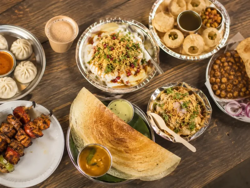 Top down view of Noida street food plates including dosa, momos, chaat, kebabs, pani puri and chole bhature