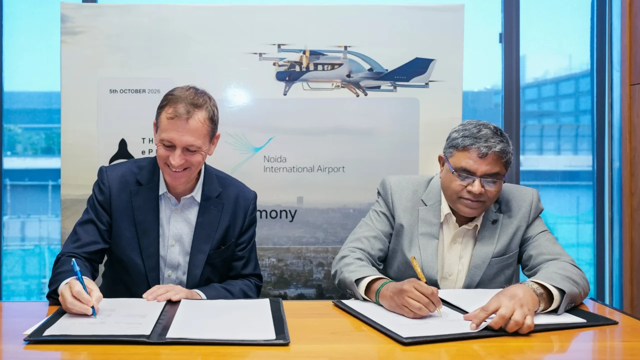 Two representatives sign documents at the Noida International Airport and ePlane partnership ceremony.