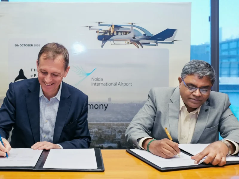 Two representatives sign documents at the Noida International Airport and ePlane partnership ceremony.